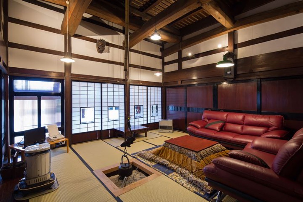 部屋の様子。冬の写真。広間で、囲炉裏・こたつ・ソファなどが置かれています。